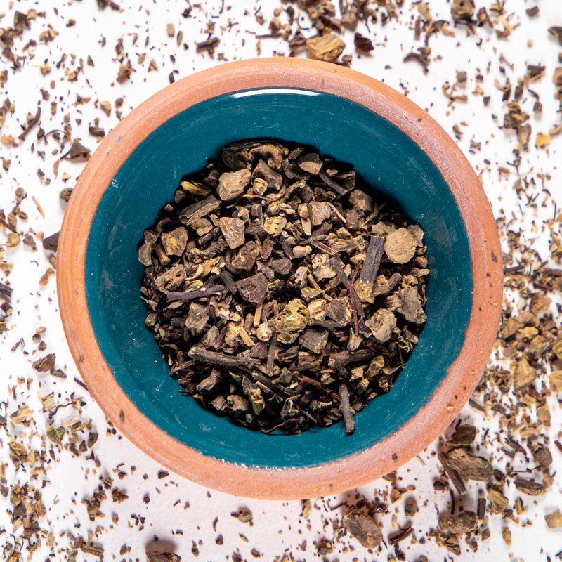 Black Cohosh Root herb in blue clay bowl with white background and herb surrounding.