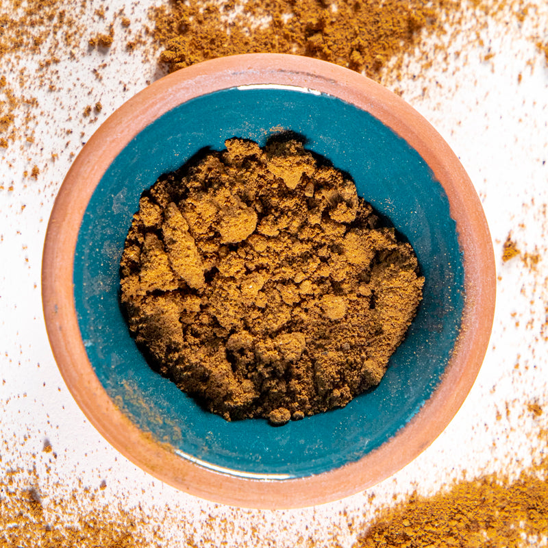 Burdock Root Powder herb in blue clay bowl with white background and herb surrounding.