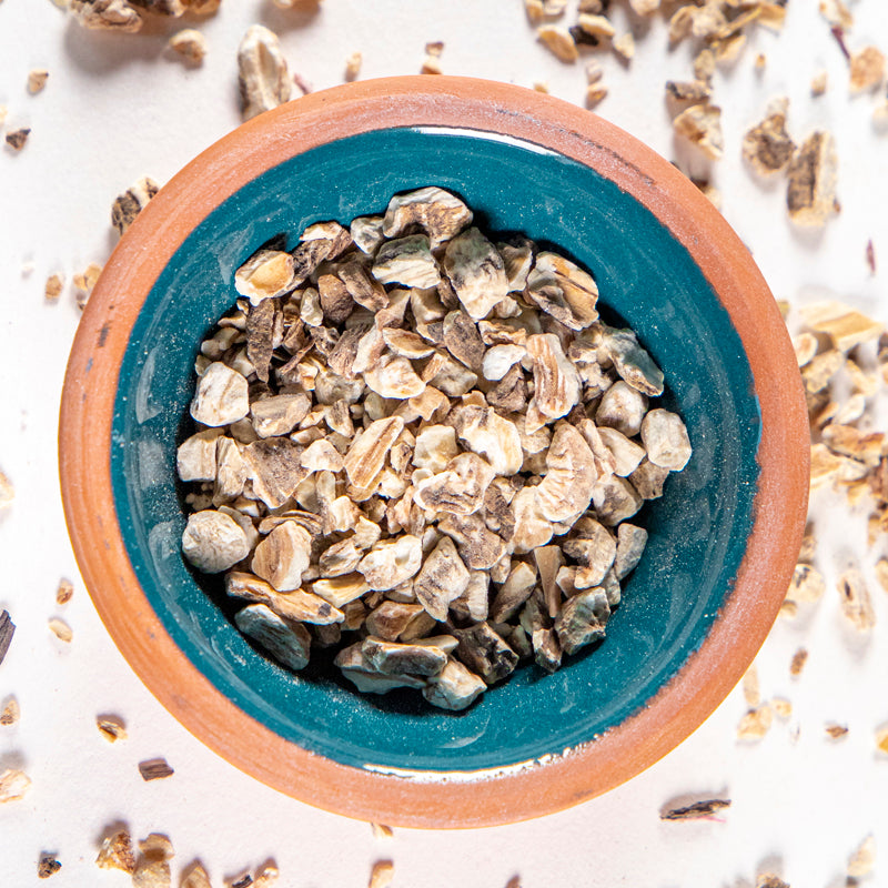 Burdock Root herb in blue clay bowl with white background and herb surrounding.