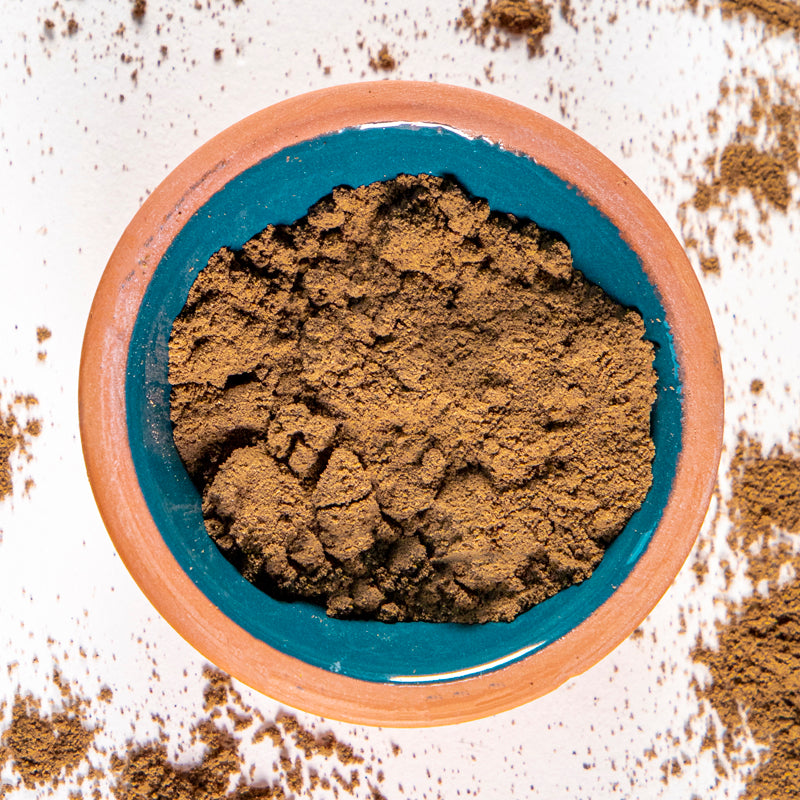 Chaste Tree Berry Powder herb in blue clay bowl with white background and herb surrounding.
