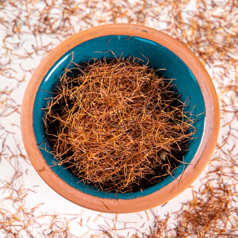 Corn Silk herb in blue clay bowl with white background and herb surrounding.