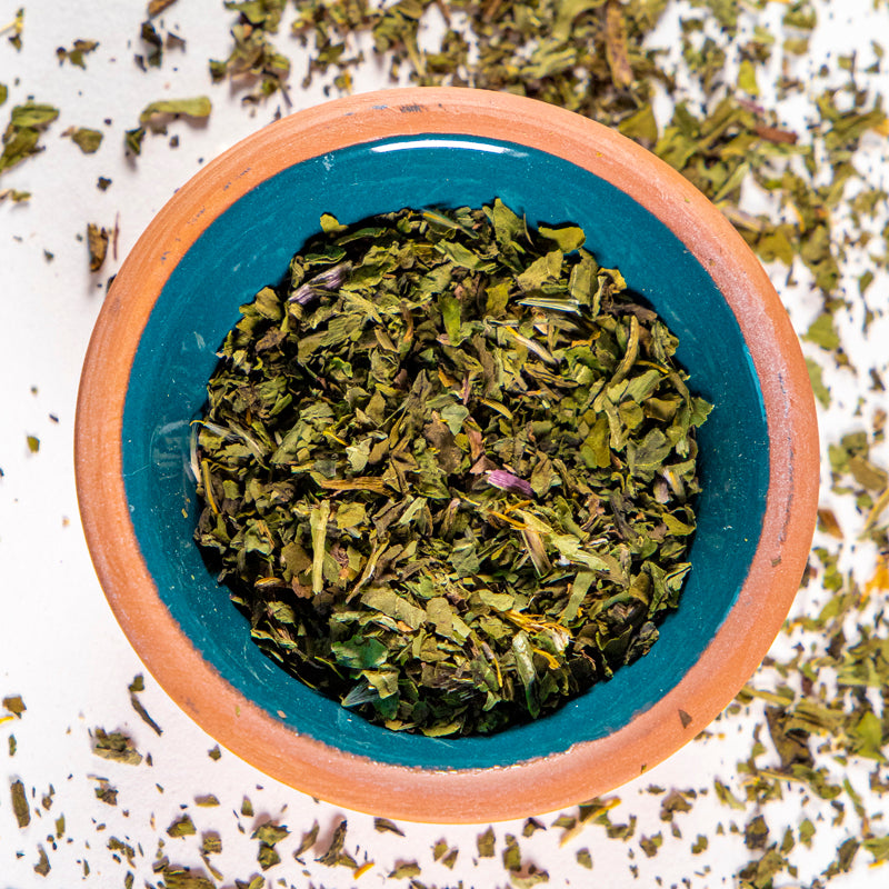 Dandelion Leaf herb in blue clay bowl with white background and herb surrounding.
