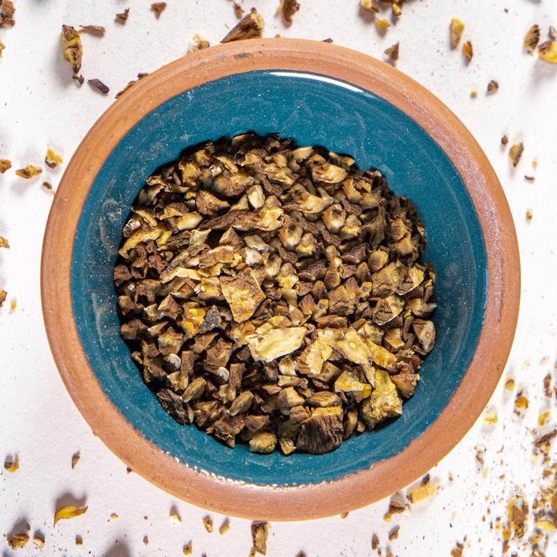 Dandelion Root herb in blue clay bowl with white background and herb surrounding.
