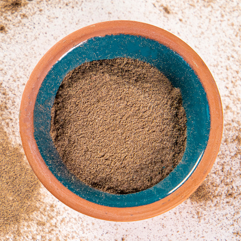 Eyebright Powder herb in blue clay bowl with white background and herb surrounding.