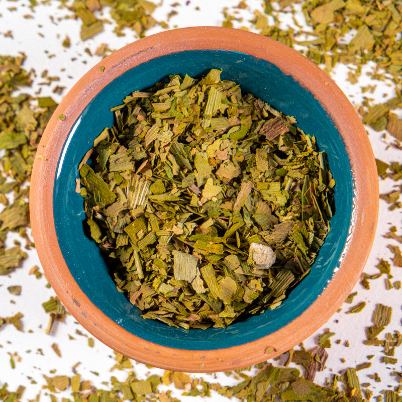 Gingko Biloba Leaves herb in blue clay bowl with white background and herb surrounding.