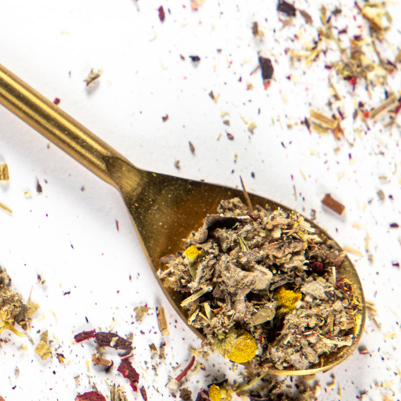 Middle Chakra Tea in a gold spoon with herbs Hibiscus ,Mullein, Mugwort, Chamomile, Clove.